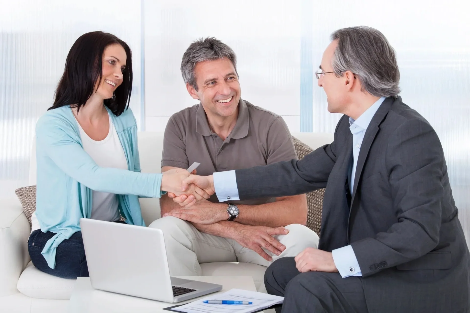 A man and woman shaking hands with an older gentleman.