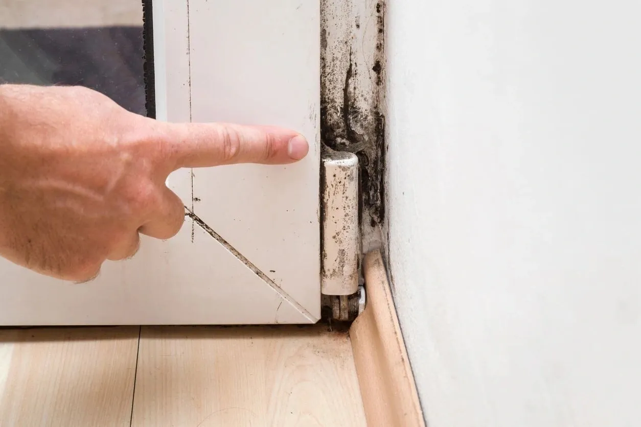 A person pointing to the door of their home.