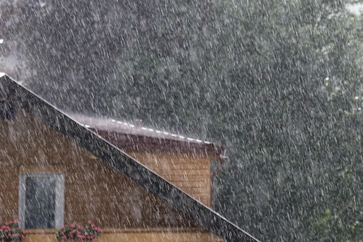 A house with a roof and a rain falling on it.